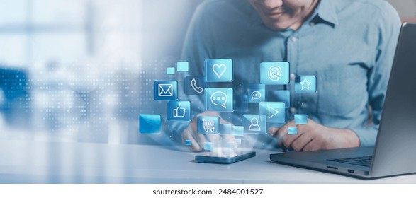 A person using a smartphone with social media icons floating around, representing social media engagement and digital communication. - Powered by Shutterstock