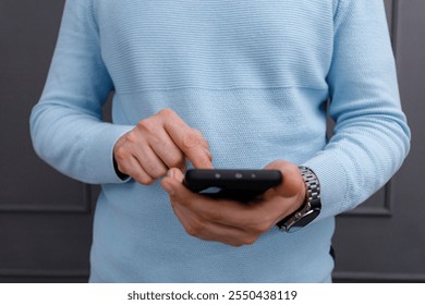 Person using smartphone while standing indoors in casual attire with a focus on digital interaction - Powered by Shutterstock