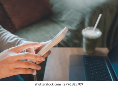 Person using  smartphone while working remotely with a laptop. Digital financial services, mobile banking, fintech applications, online account management and modern technology lifestyle concept.