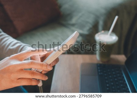 Person using  smartphone while working remotely with a laptop. Digital financial services, mobile banking, fintech applications, online account management and modern technology lifestyle concept.