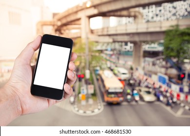 Person Using Smartphone White Screen Holder On Hand With  Blurry Of Traffic Jam On The City Street In Bangkok Thailand.