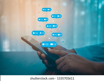Person Using A Social Media Marketing Concept On Mobile Phone With Notification Icons Of Like, Message, Comment And Star Above Smartphone Screen.