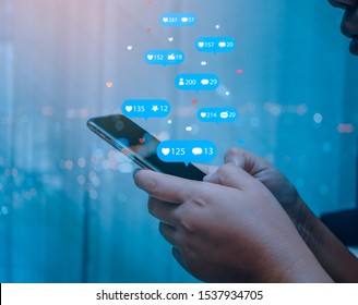 Person Using A Social Media Marketing Concept On Mobile Phone With Notification Icons Of Like, Message, Comment And Star Above Mobile Phone Screen.