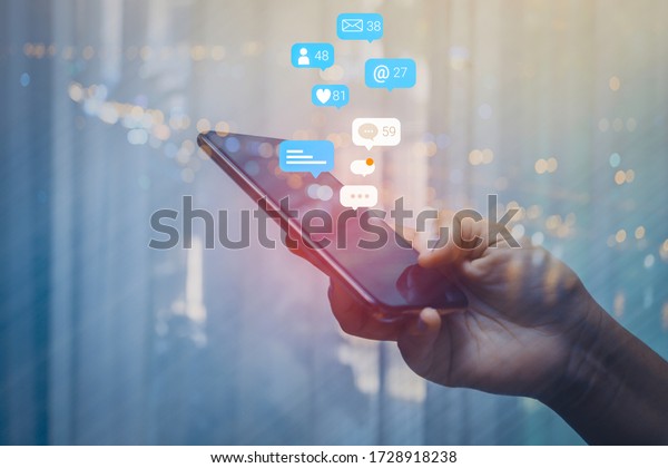 Person using a social media marketing\
concept on mobile phone with notification icons of like, message,\
comment and star above smartphone\
screen.
