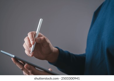 A person using a stylus to write or draw on a digital tablet, highlighting modern technology in everyday tasks.