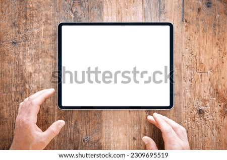 Person using tablet computer on wooden table, blank white screen mockup
