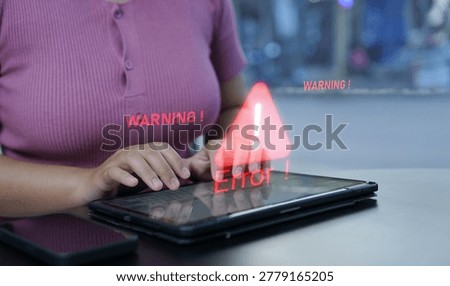 A person using a tablet faces a digital warning and error alert, highlighting a technical issue or cybersecurity threat on the device.