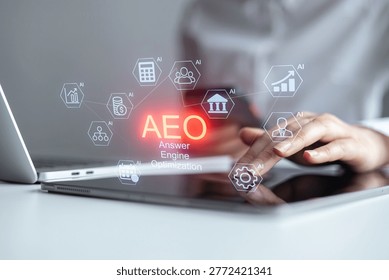A person is using a tablet while sitting at a desk with a laptop. Various icons representing answer engine optimization appear on the tablet screen. It is daytime.