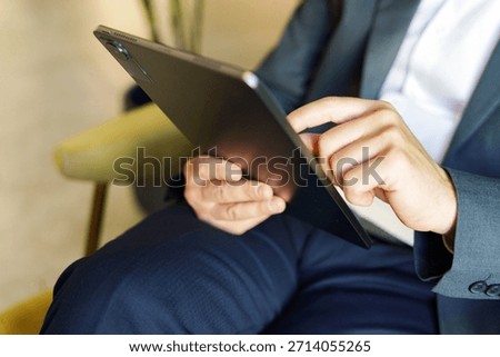 Person using tablet while sitting in chair indoors