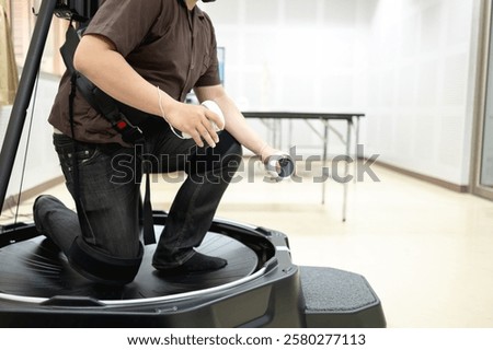 Person using a VR treadmill with controllers, engaging in a virtual reality experience for immersive movement simulation.