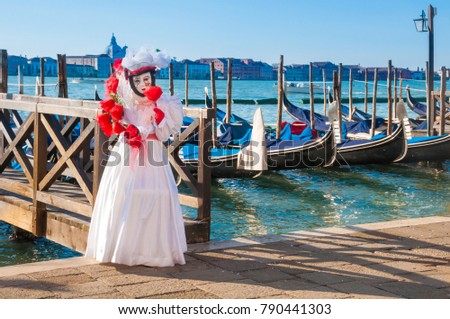 Person with venitian carnival mask in front of gondolas during Venice carnival