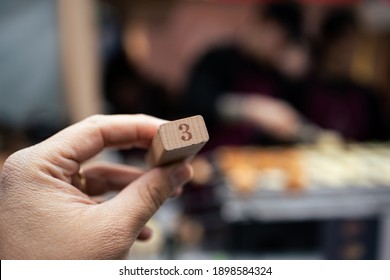 A Person Waiting With A Wooden Block With The Number 3 On It In Hands