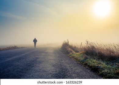A person walk into the misty foggy road in a dramatic mystic sunrise scene with abstract colors