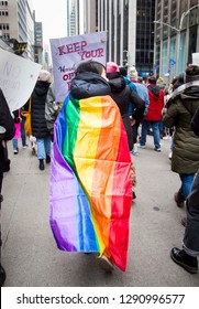 Person Walking Down The Street Wearing The Pride Flag As A Cape During The NYC Women's March -  New York, NY, USA January 1/19/2019 Women's March