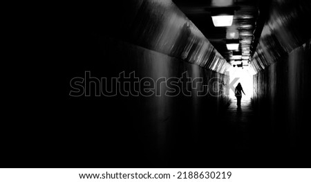 Person walking through a tunnel towards light at end. Accomplishing goal or leaving darkness.