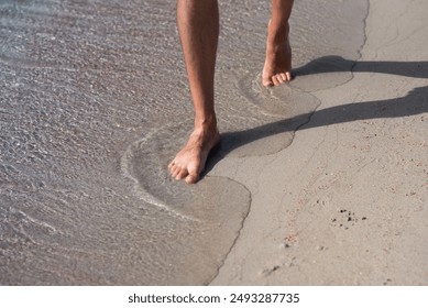 A person walks barefoot along the beach shoreline, enjoying the serene and calming morning atmosphere. - Powered by Shutterstock