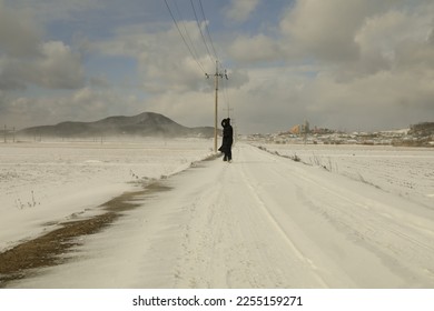 A person walks through a field filled with white snow.
