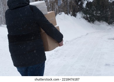 person wearing black winter jacket and cap delivering parcels in the winter