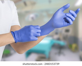 A person wearing blue medical gloves, preparing for a procedure in a clinical or hospital setting. - Powered by Shutterstock