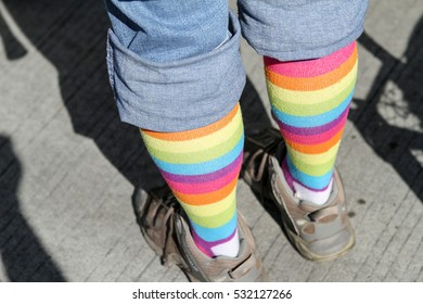 Person Wearing Crazy Rainbow Socks And Dirty Shoes.  