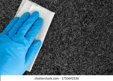 Person Wearing Gloves Cleaning Granite Kitchen Worktop Counter With An Anti-bacterial Wipe Cloth.  Killing Bacteria And Germs Concept