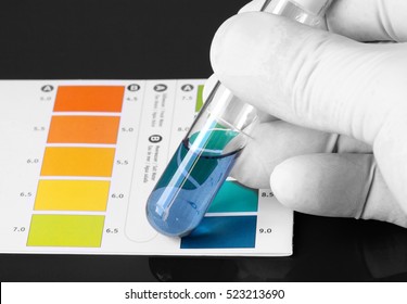 Person wearing gloves testing the PH of a chemical in a test tube