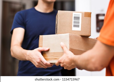 A person wearing an orange T-shirt is delivering parcels to a satisfied client. Friendly worker, high quality delivery service. - Shutterstock ID 1154715967