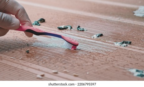 Person Wearing Protective Latex Gloves Cleaning Bird Poop Droppings From Composite Plank Floor On Balcony Using Paper Towel