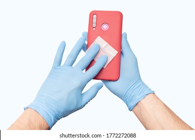 A Person Wearing Protective Medical Gloves Wipes His Mobile Phone With A Disinfectant, As One Of The Main Carriers Of Bacteria And Viruses. The Concept Of The Coronavirus Kovid-19 And OCD