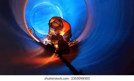 person wearing welding mask Welding a circular pipe from the inside - Powered by Shutterstock