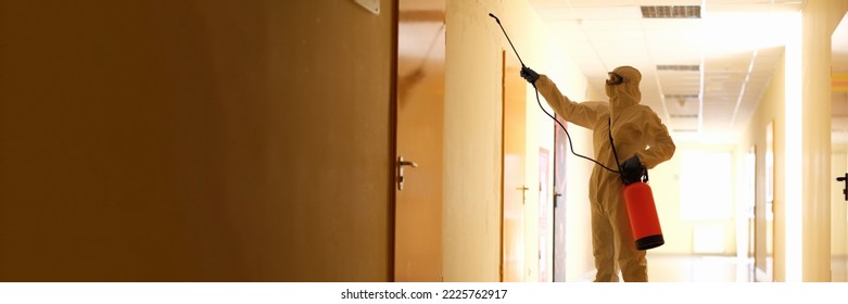 Person Wearing White Chemical Protection Suit Holding Spray Bottle With Disinfectant Chemicals