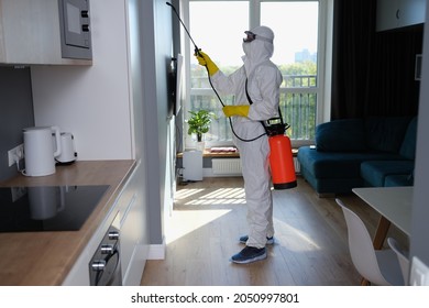 Person in white protective suit, mask and gloves with balloon disinfection in kitchen - Powered by Shutterstock