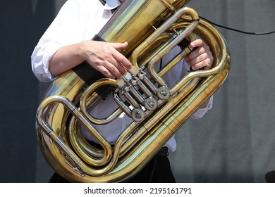 A person in a white shirt playing a musical instrument tuba close-up