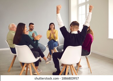 Person Who Managed To Cope With Problem And To Overcome Addiction. Diverse People Sitting In Circle In Group Therapy Meeting And Applauding Happy Young Patient, Celebrating His Successful Recovery