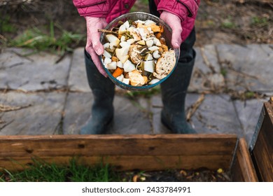 Person who put in a composter some kitchen waste like vegetables, fruits, eggshell, coffee grounds in order to sort and make bio fertilizer - Powered by Shutterstock