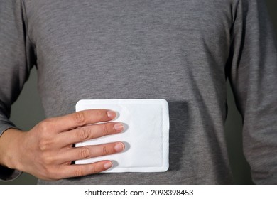 A person who puts a disposable heat pack on his stomach