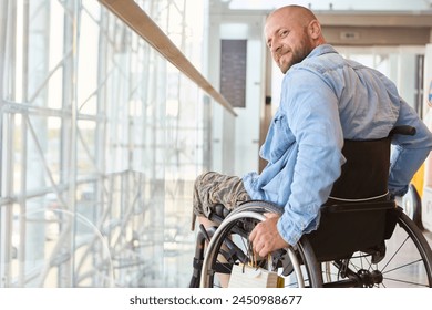 A person who uses a wheelchair is pictured smiling warmly in a well-lit, modern building, showcasing a moment of joy and accessibility. - Powered by Shutterstock