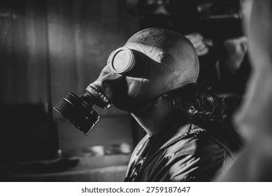 A person whose face is hidden behind a rubber gas mask with large round glasses that reflect light. Only a portion of his hair is visible, spilling out from under his rubber hat. High quality photo