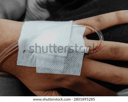 a person whose left hand is on an IV drip