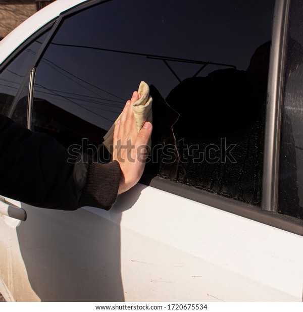 A person wipes the\
car window with a wet rubberized cloth. Hand wiping of the car from\
dirt and dust.