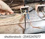 A person is working on connecting multiple colored electrical wires to a junction box in a residential basement.