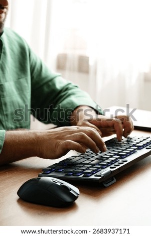 Person working on a keyboard while using a computer mouse in a well-lit room