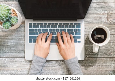 Person Working On A Laptop Computer Overhead View On A Wooden Desk