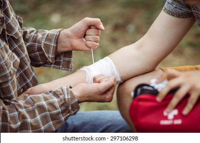 A person wrapping his friends injured arm in gauze