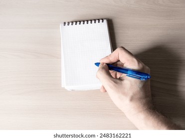 Person write in Notepad on a Table closeup