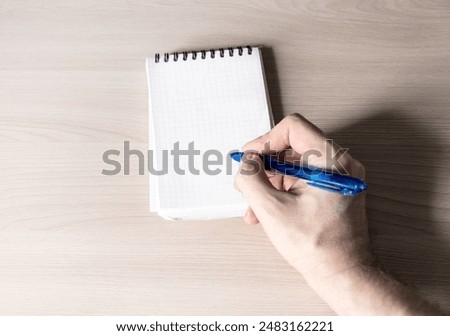 Person write in Notepad on a Table closeup