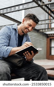 A person writes in a notebook while sitting on a park bench