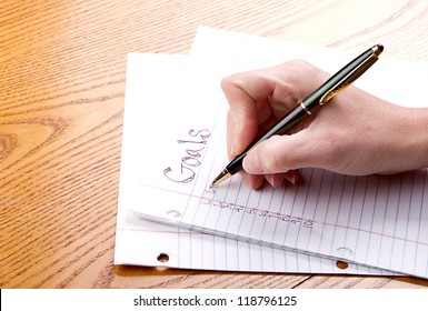 Person writing goals on a paper