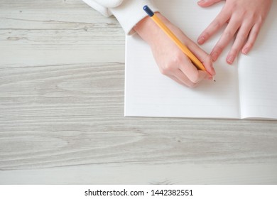  Person writing letters on notebook at table                              