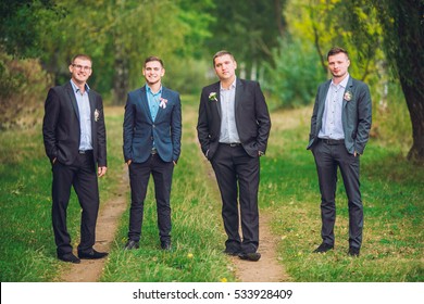 Personable groom with best mans or groomsman posed on park at wedding day.